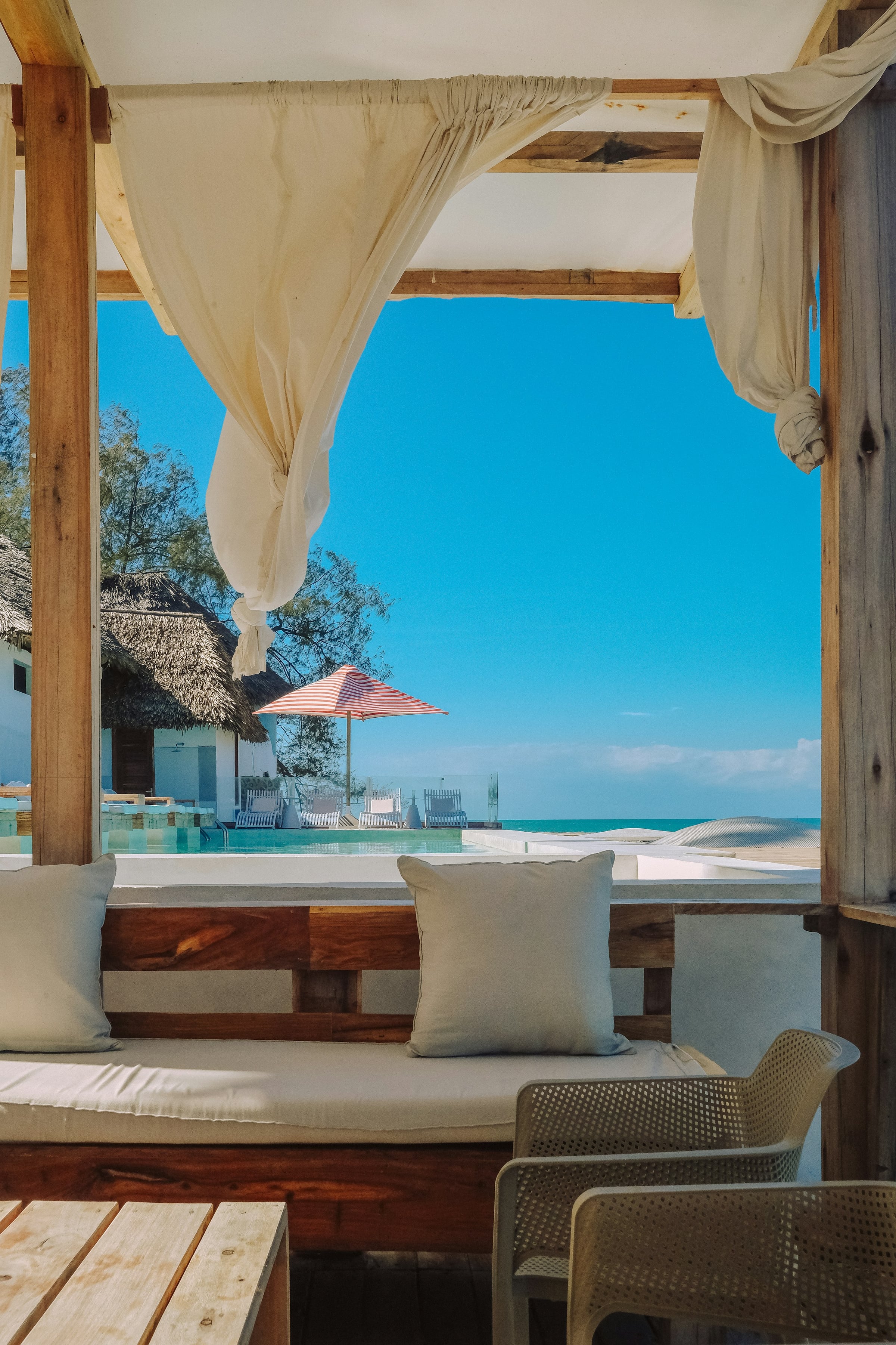 Linen cabana curtains framing an oceanfront pool, Los Cabos-style luxury resort