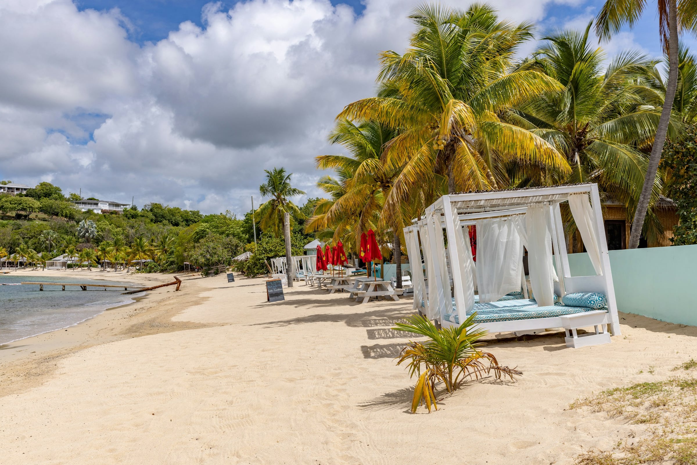 White beach cabana with sheer curtains among palm trees